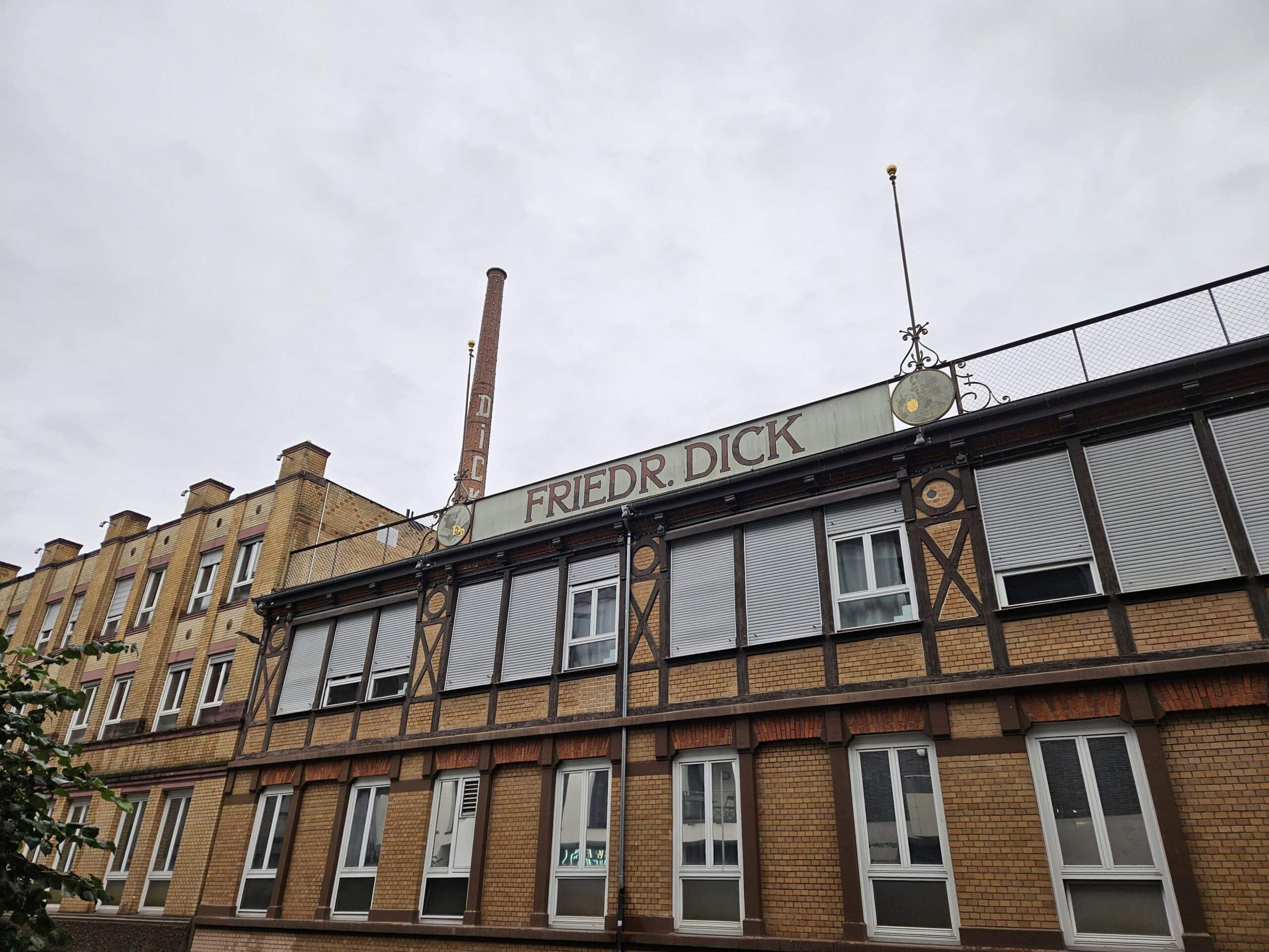 Industrielles Backsteingebäude mit "Friedr. Dick" Schild, bewölkter Himmel, historisches Design.