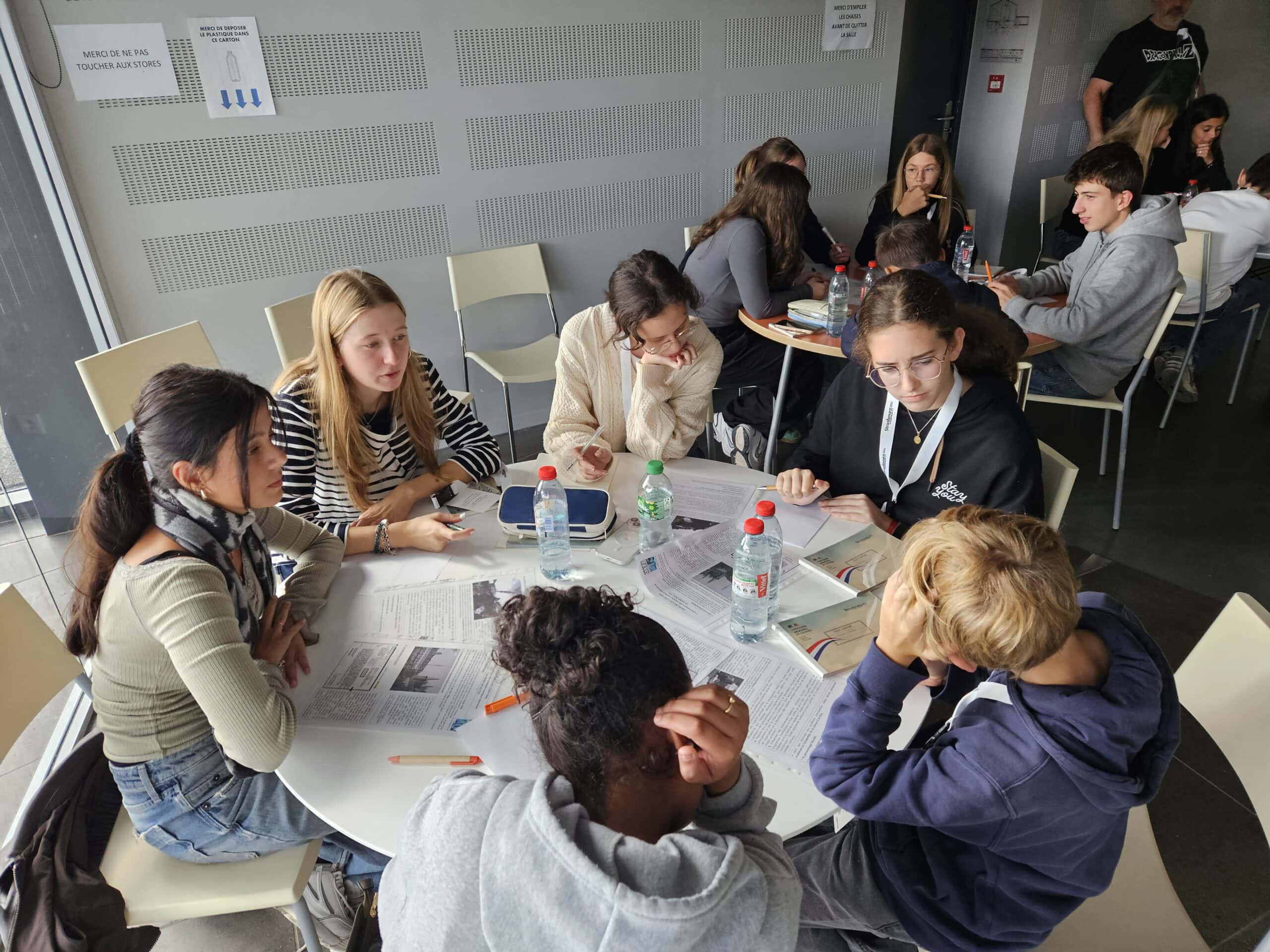 Junge Erwachsene diskutieren in einem Gruppenraum um einen Tisch; Fokus auf Zusammenarbeit und Austausch.