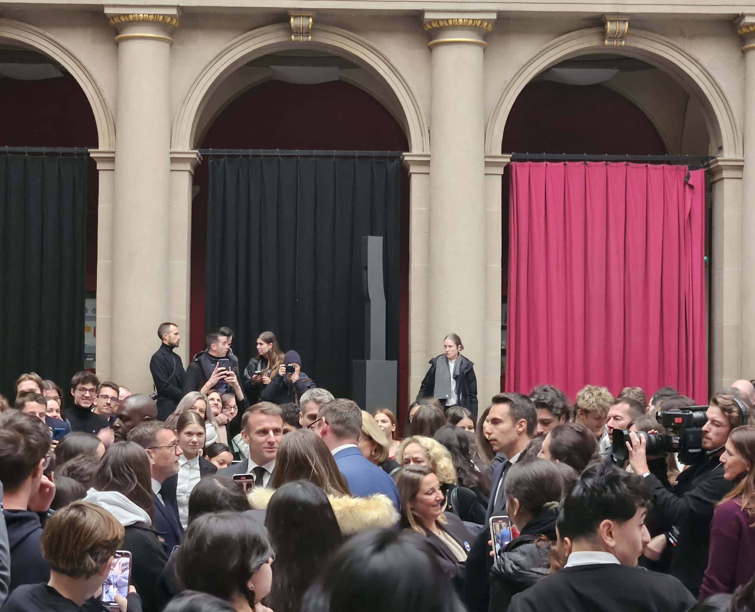 Eine Menschenmenge in einem eleganten Gebäude, einige Leute fotografieren, teils in Gespräch vertieft.