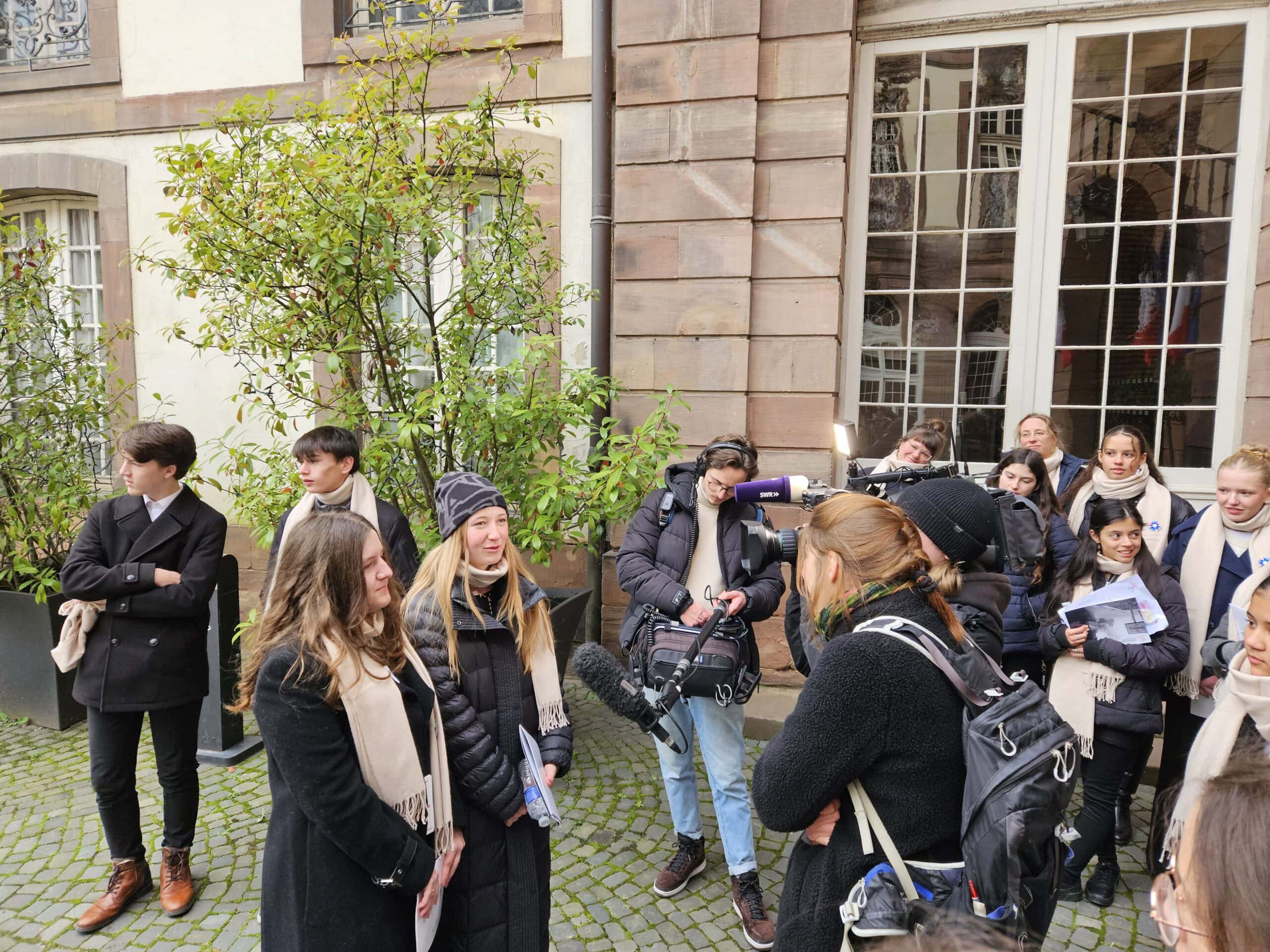 Gruppe von Menschen im Freien, freundlich, vor einem Gebäude interviewt von Reportern.