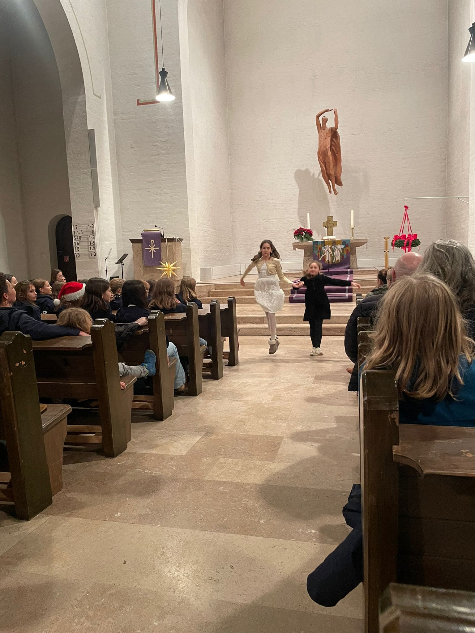 Eine Frau und ein Kind tanzen lächelnd in einer Kirche, umgeben von Zuschauern.